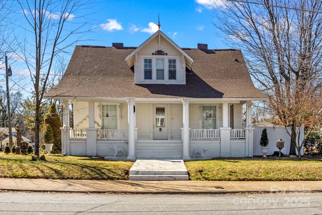 bungalow-style home featuring a porch, a front lawn, a chimney, and fence