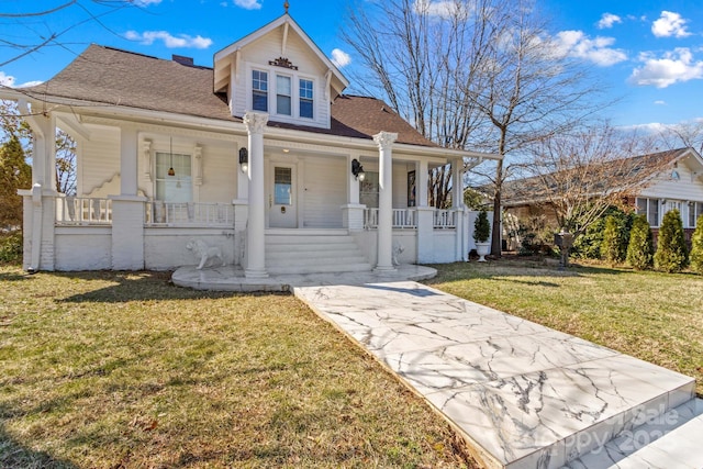 view of front of property with a porch, a front yard, and a shingled roof