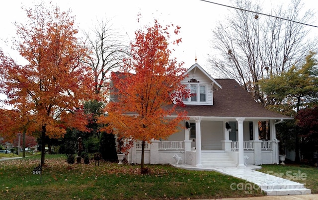 view of front of home featuring a porch, a shingled roof, and a front lawn