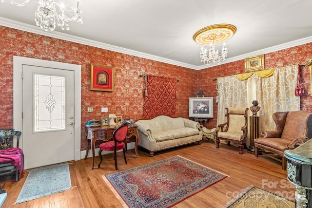 living room with ornamental molding, wood finished floors, and an inviting chandelier