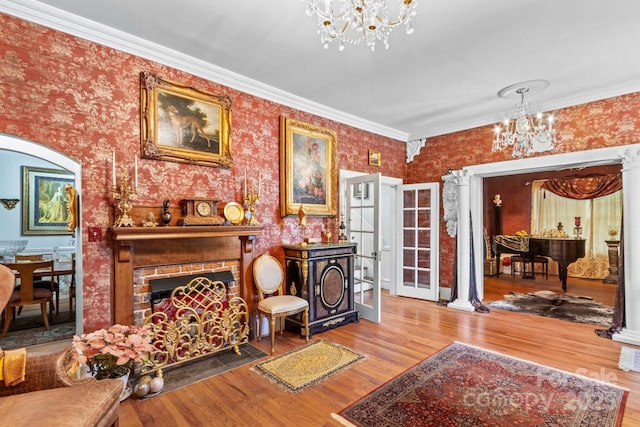 living room with arched walkways, crown molding, a fireplace, a notable chandelier, and wood finished floors