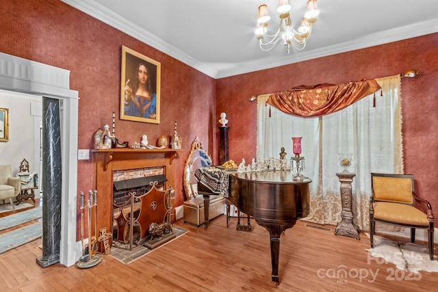 living area featuring a fireplace with flush hearth, crown molding, an inviting chandelier, and wood finished floors