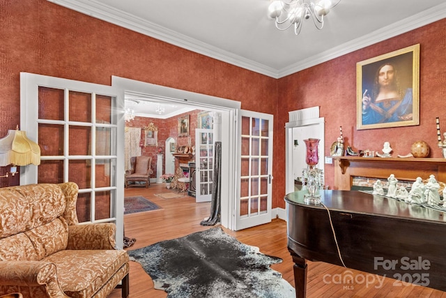 living area featuring a chandelier, ornamental molding, and wood finished floors