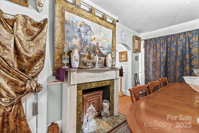 dining area featuring a fireplace, wood finished floors, and crown molding