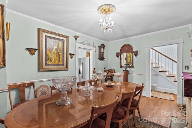 dining area with baseboards, crown molding, an inviting chandelier, and wood finished floors