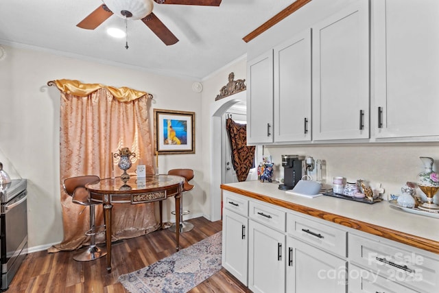 kitchen with ornamental molding, arched walkways, light countertops, and wood finished floors