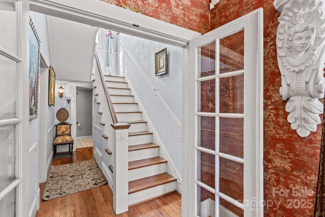 staircase featuring wallpapered walls and wood finished floors