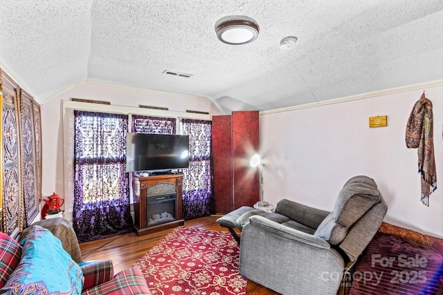 living room featuring lofted ceiling, visible vents, a textured ceiling, and wood finished floors