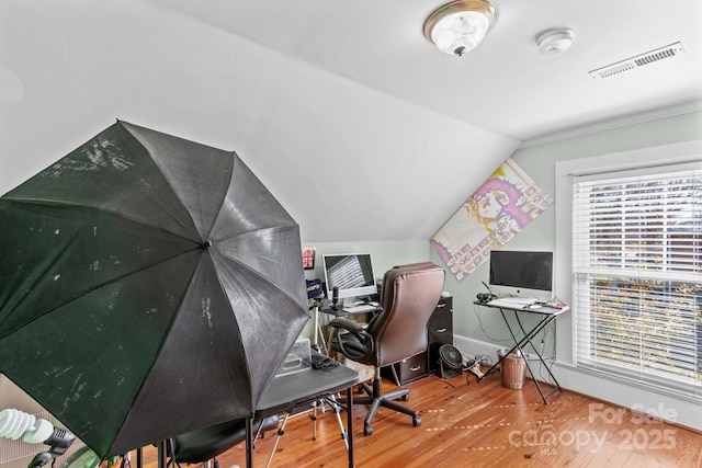 home office featuring lofted ceiling, baseboards, visible vents, and wood finished floors