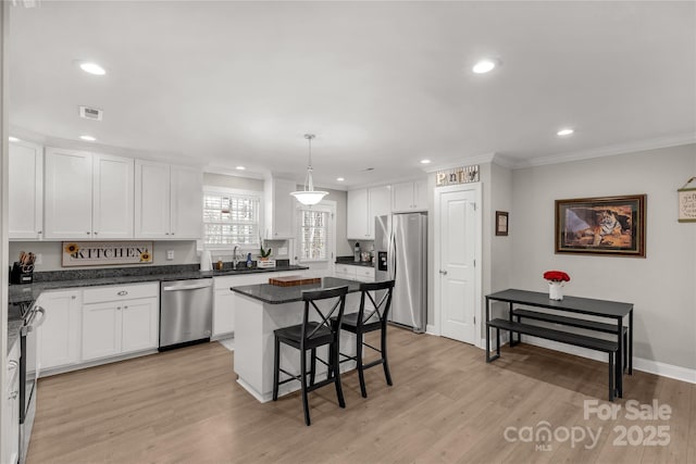 kitchen with white cabinetry, appliances with stainless steel finishes, a kitchen island, and pendant lighting
