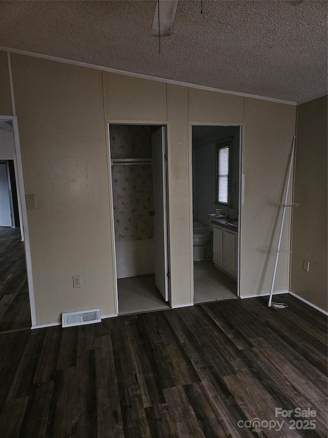 unfurnished bedroom featuring a closet, ornamental molding, dark hardwood / wood-style flooring, and a textured ceiling