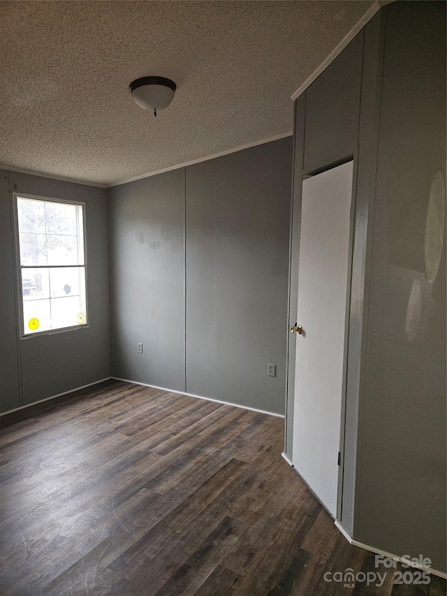 empty room with ornamental molding, a textured ceiling, and dark hardwood / wood-style flooring