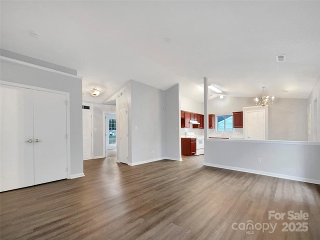 unfurnished living room with a chandelier, vaulted ceiling, and hardwood / wood-style floors