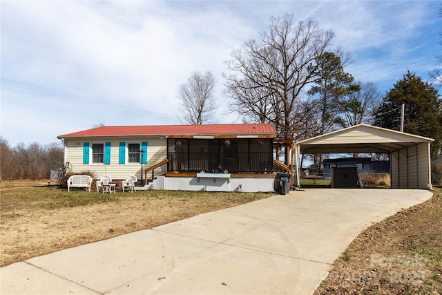 manufactured / mobile home with a sunroom, entry steps, concrete driveway, a carport, and metal roof