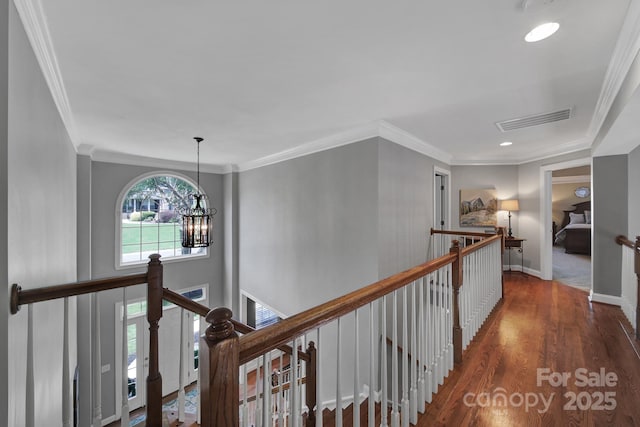 hall featuring dark wood-type flooring, crown molding, and an inviting chandelier