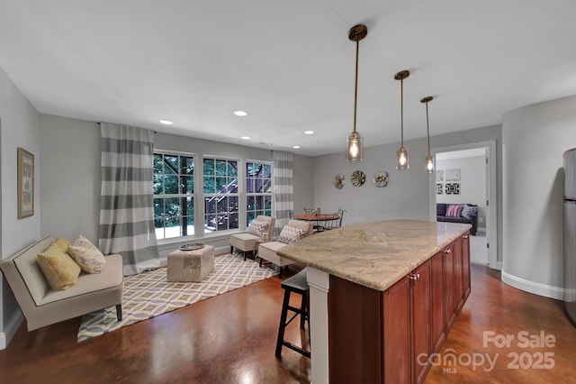 kitchen with a center island, a breakfast bar area, light stone counters, and decorative light fixtures