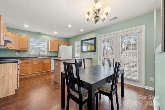 dining room featuring dark hardwood / wood-style flooring, sink, a textured ceiling, and an inviting chandelier