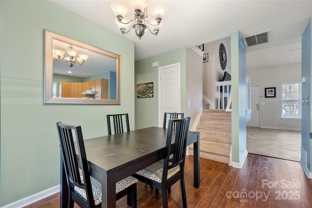 dining area with dark hardwood / wood-style floors and a notable chandelier