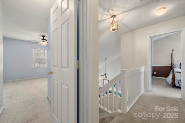 hallway with light colored carpet and a textured ceiling