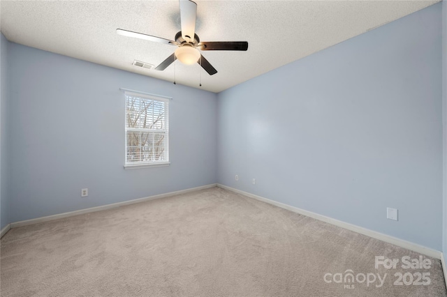 empty room featuring a textured ceiling, light colored carpet, and ceiling fan