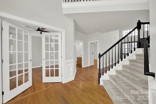 foyer entrance featuring wood finished floors, stairway, french doors, and ceiling fan