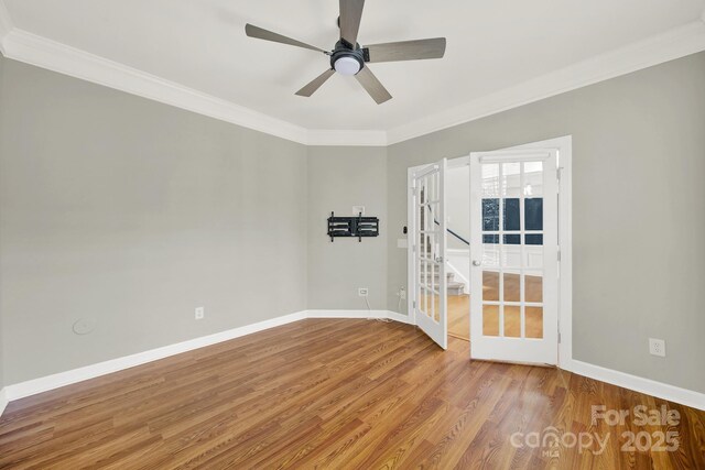 spare room with a ceiling fan, wood finished floors, baseboards, and ornamental molding