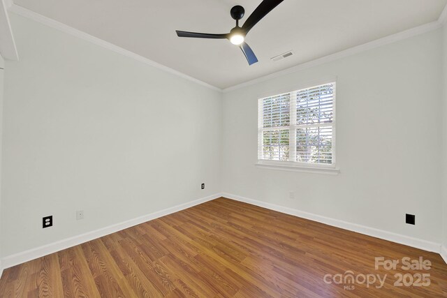 spare room featuring ceiling fan, baseboards, wood finished floors, and crown molding