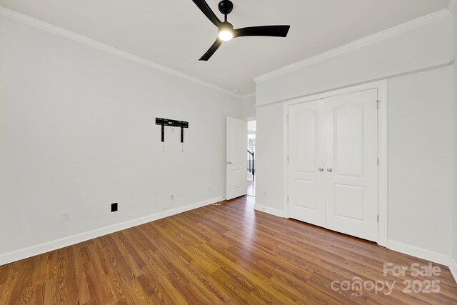 unfurnished bedroom with ornamental molding, a ceiling fan, wood finished floors, a closet, and baseboards