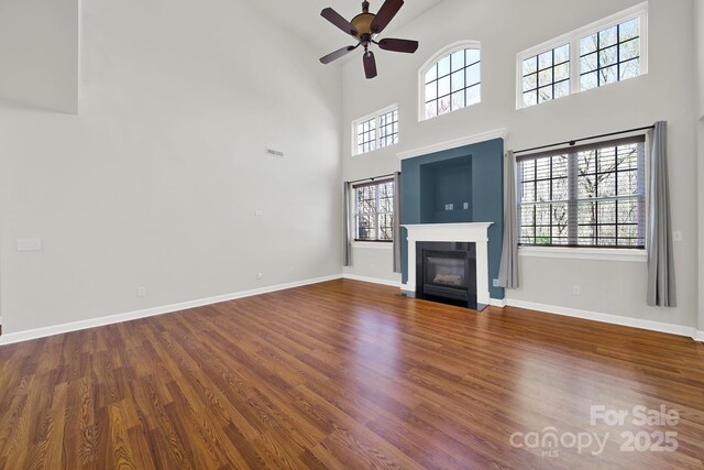 unfurnished living room with baseboards, a fireplace with flush hearth, and wood finished floors