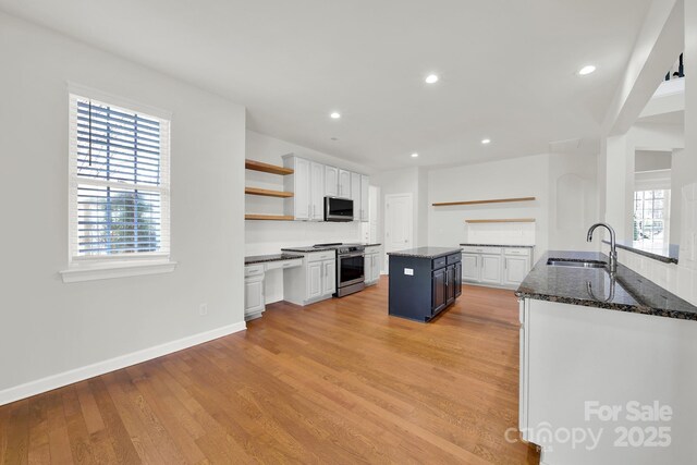 kitchen with light wood-type flooring, open shelves, a sink, white cabinetry, and appliances with stainless steel finishes