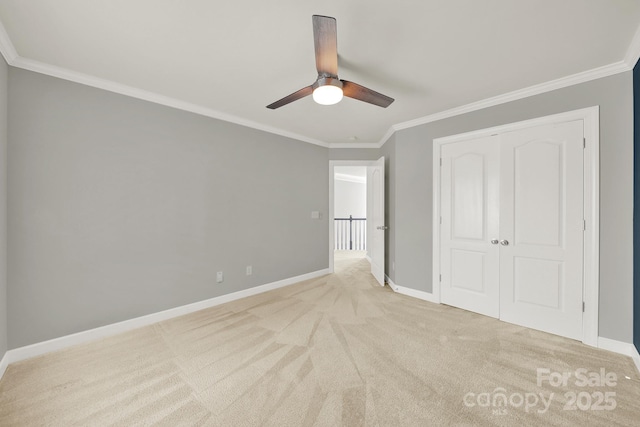 unfurnished bedroom featuring a ceiling fan, carpet, baseboards, a closet, and crown molding