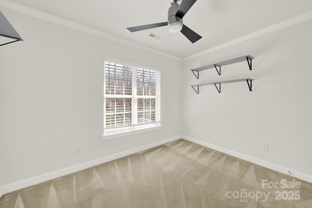 carpeted spare room with stairway, a ceiling fan, baseboards, visible vents, and crown molding