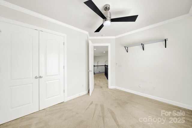 unfurnished bedroom with a ceiling fan, a closet, carpet flooring, crown molding, and baseboards