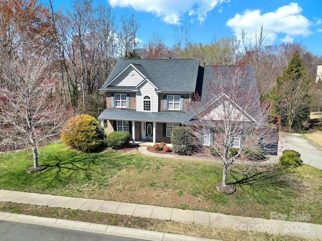 view of front of property with a front yard, concrete driveway, and brick siding