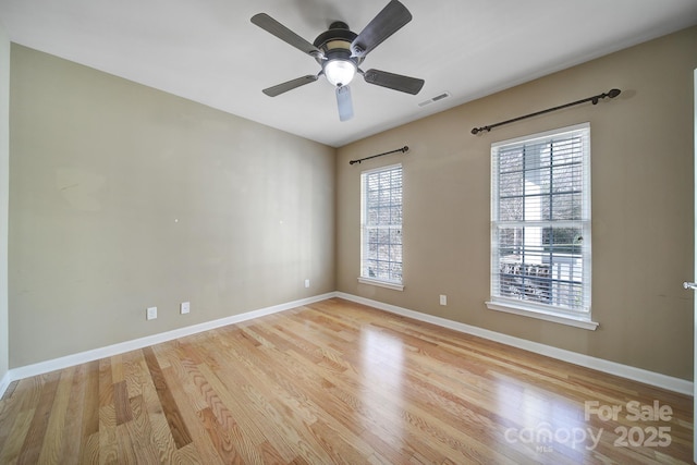 empty room with light wood-style flooring, a ceiling fan, visible vents, and baseboards