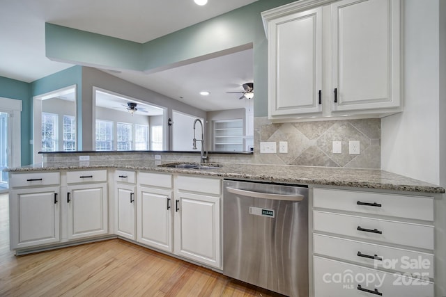 kitchen featuring tasteful backsplash, dishwasher, light wood-type flooring, white cabinetry, and a sink