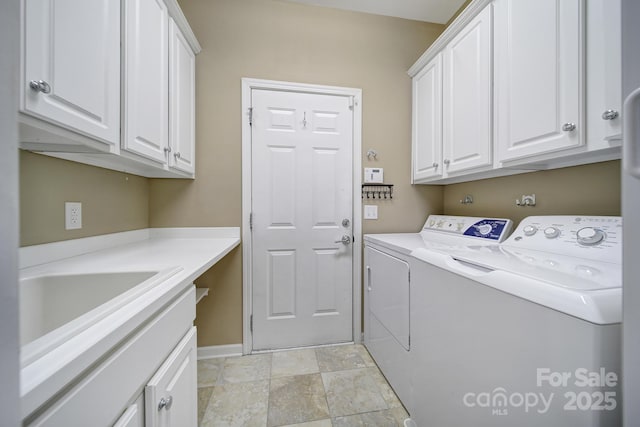 clothes washing area featuring washer and clothes dryer, cabinet space, and baseboards