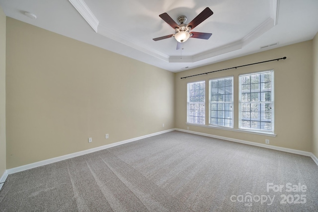 carpeted empty room featuring a raised ceiling, visible vents, ornamental molding, ceiling fan, and baseboards