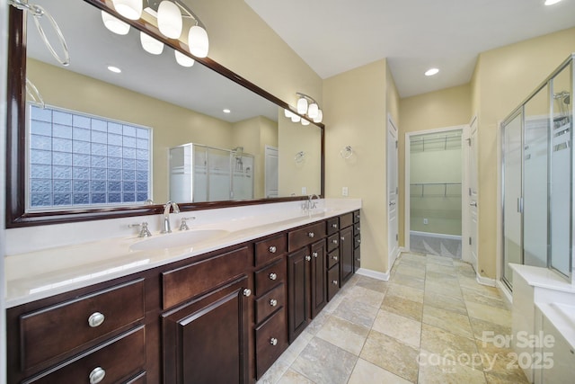 full bathroom featuring recessed lighting, a sink, double vanity, a stall shower, and a walk in closet