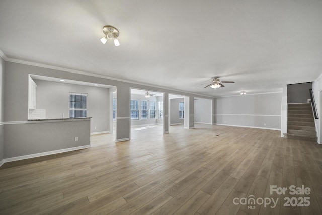 unfurnished living room featuring crown molding, stairway, ceiling fan, and wood finished floors