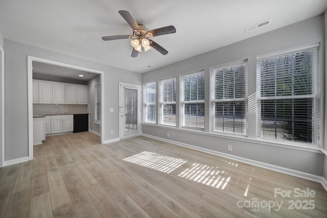 unfurnished living room featuring baseboards, visible vents, ceiling fan, and light wood finished floors