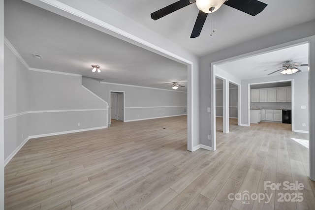 unfurnished living room with ornamental molding, light wood-type flooring, visible vents, and baseboards