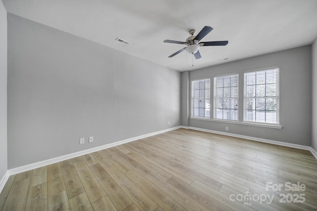 unfurnished room with a ceiling fan, baseboards, visible vents, and wood finished floors