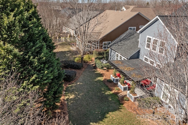 exterior space with a garden, a shingled roof, and a yard