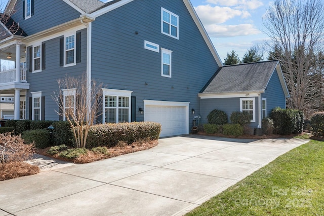 view of front facade featuring a garage, concrete driveway, and roof with shingles