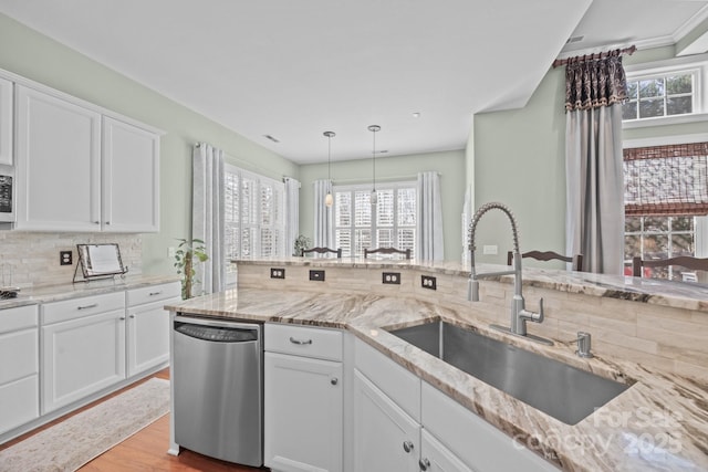 kitchen featuring dishwasher, decorative light fixtures, light stone countertops, white cabinetry, and a sink