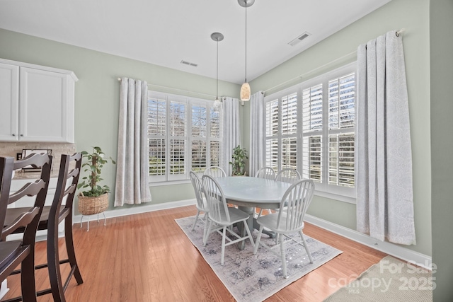 dining area featuring visible vents, light wood-style flooring, and baseboards