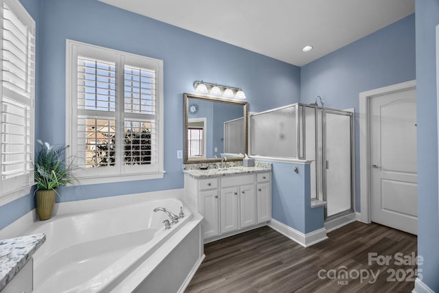 bathroom with a garden tub, recessed lighting, a stall shower, vanity, and wood finished floors