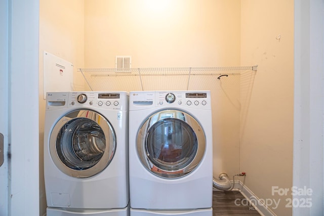 washroom with laundry area, washing machine and dryer, visible vents, and dark wood-style flooring