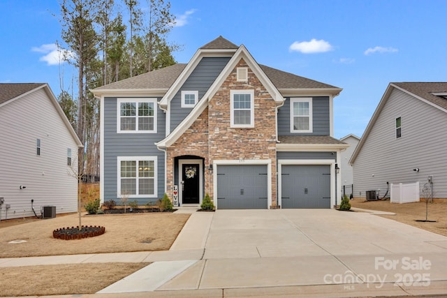 view of front of house with a garage, stone siding, central AC, and driveway